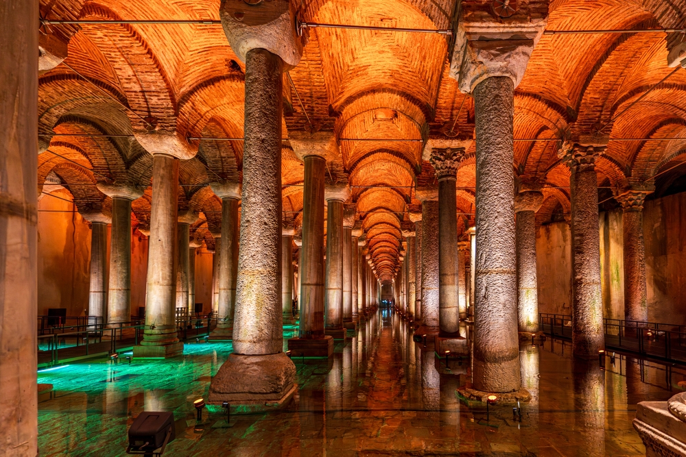 Interno della Basilica Cisterna con colonne illuminate e riflessi sull'acqua.